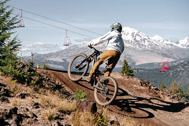 Biker in the Mt. Bachelor Bike Park with Red Chair and the Cascade Range in the background