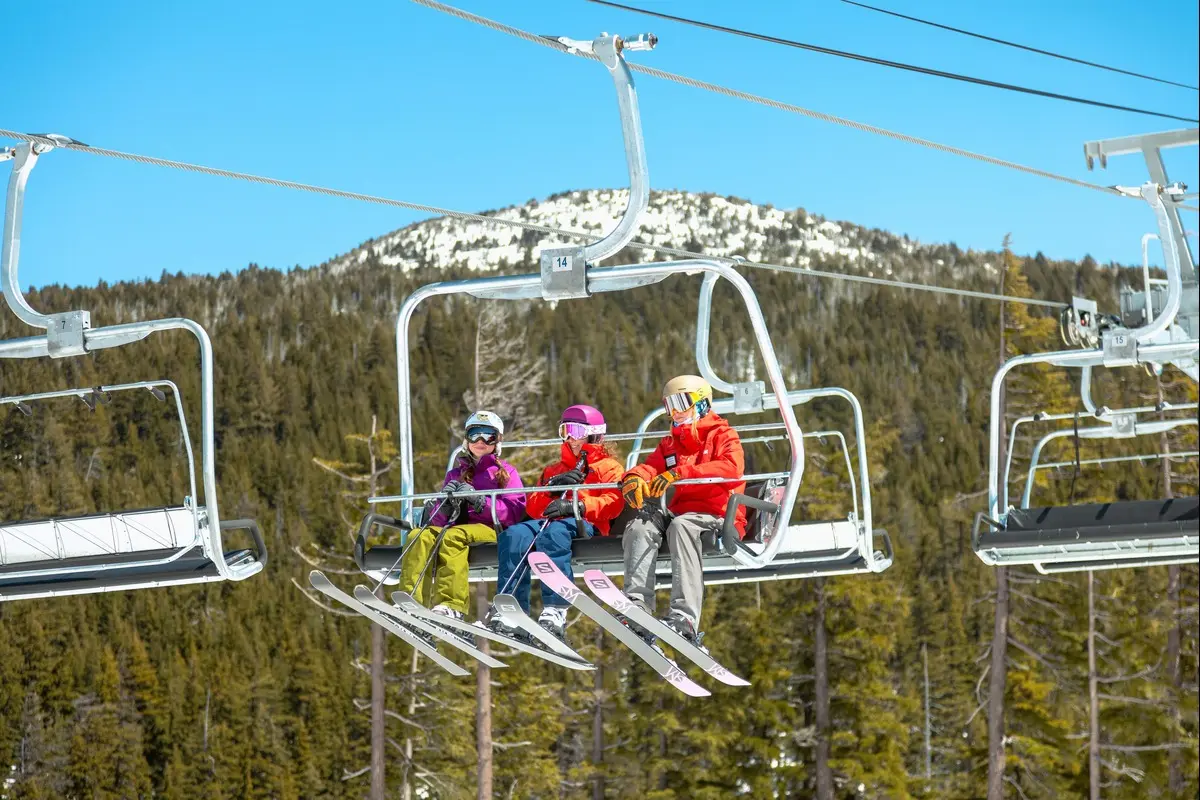 group of kids learning to ski and ride the chair lift for the first time.